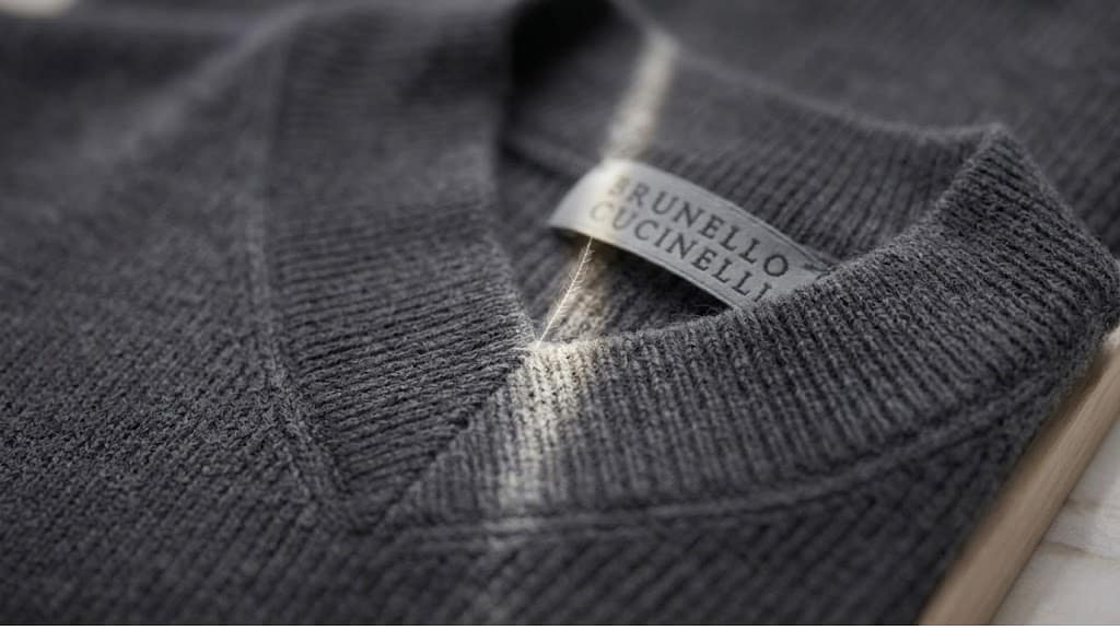 cashmere v neck sweater Brunello Cucinelli grey knit displayed on stand with premium fabric texture highlights.