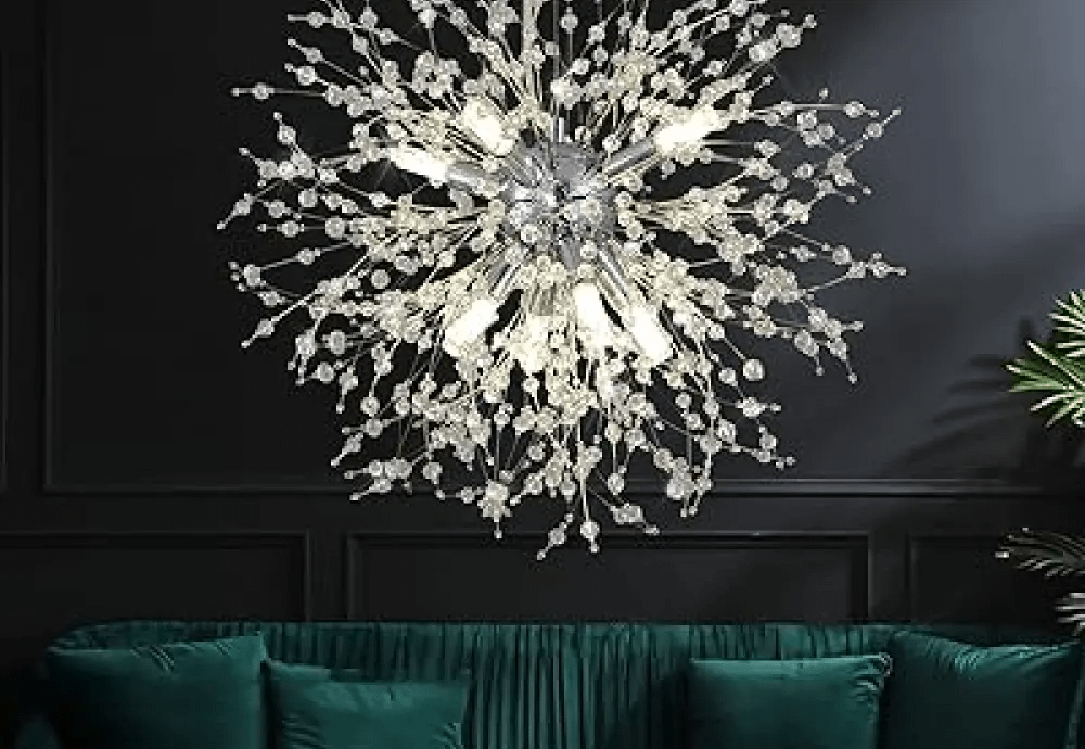 Crystal burst chandelier over green velvet sofa on dark wall.